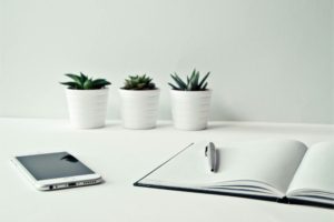 A pen and notebook on a table source: Photo by Ylanite Koppens: https://www.pexels.com/photo/three-white-ceramic-pots-with-green-leaf-plants-near-open-notebook-with-click-pen-on-top-796602/