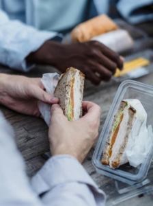 A person holding a sandwich that came out of plastic packaging. Source: Photo by Mizuno K from Pexels: https://www.pexels.com/photo/man-holding-a-sandwich-13335061/