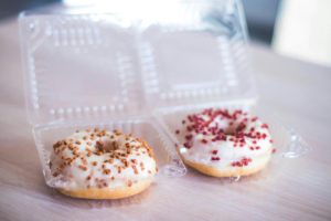 Two donuts with sprinkles in a plastic container Source: Photo by Valeria Boltneva: https://www.pexels.com/photo/two-donuts-in-clear-plastic-packs-1028431/